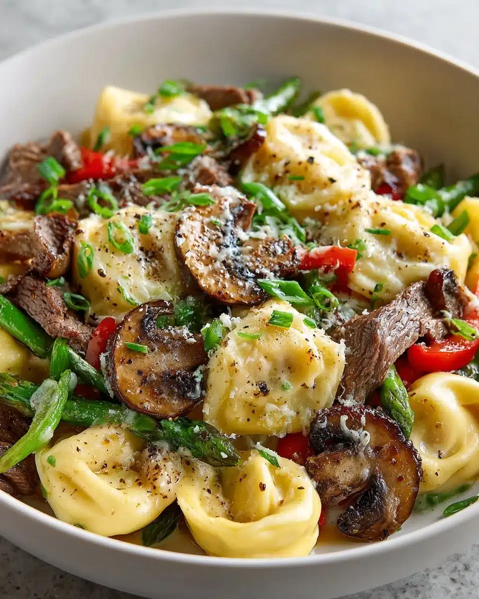 Delicious cheesesteak tortellini dish topped with herbs and cheese