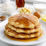 Fluffy cinnamon apple pancakes topped with maple syrup on a plate